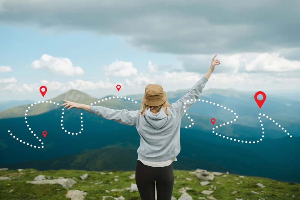 Traveling,Caucasian,Female,Traveler,Explorer,Rise,Hand,Up,Hiking,To Person standing overlooking a mountain field with a map grapically overlayed